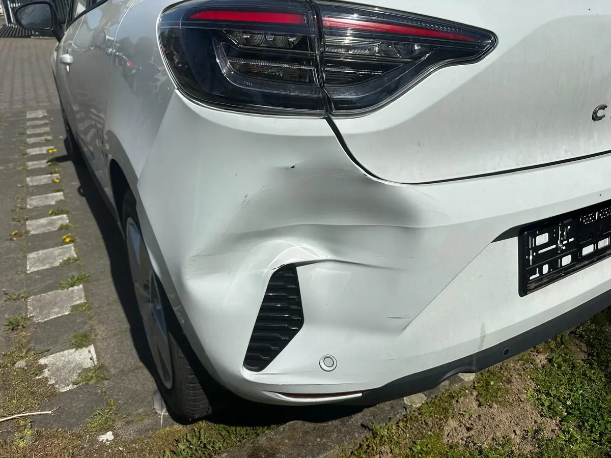 Weißer Renault Clio mit eingedrücktem hinteren Stoßfänger, Kennzeichen entfernt