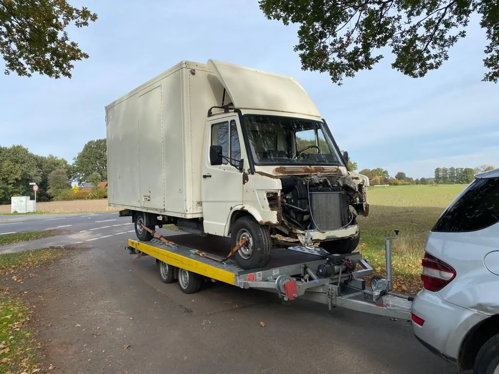 Älterer weißer Koffer-Lkw mit beschädigter Front auf unserem Autoanhänger