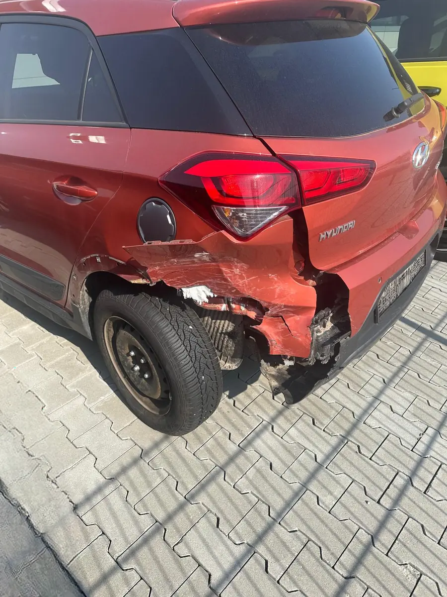 Roter Hyundai i20 mit Heckschaden: Seitenwand hinten und Stoßfänger aufgerissen