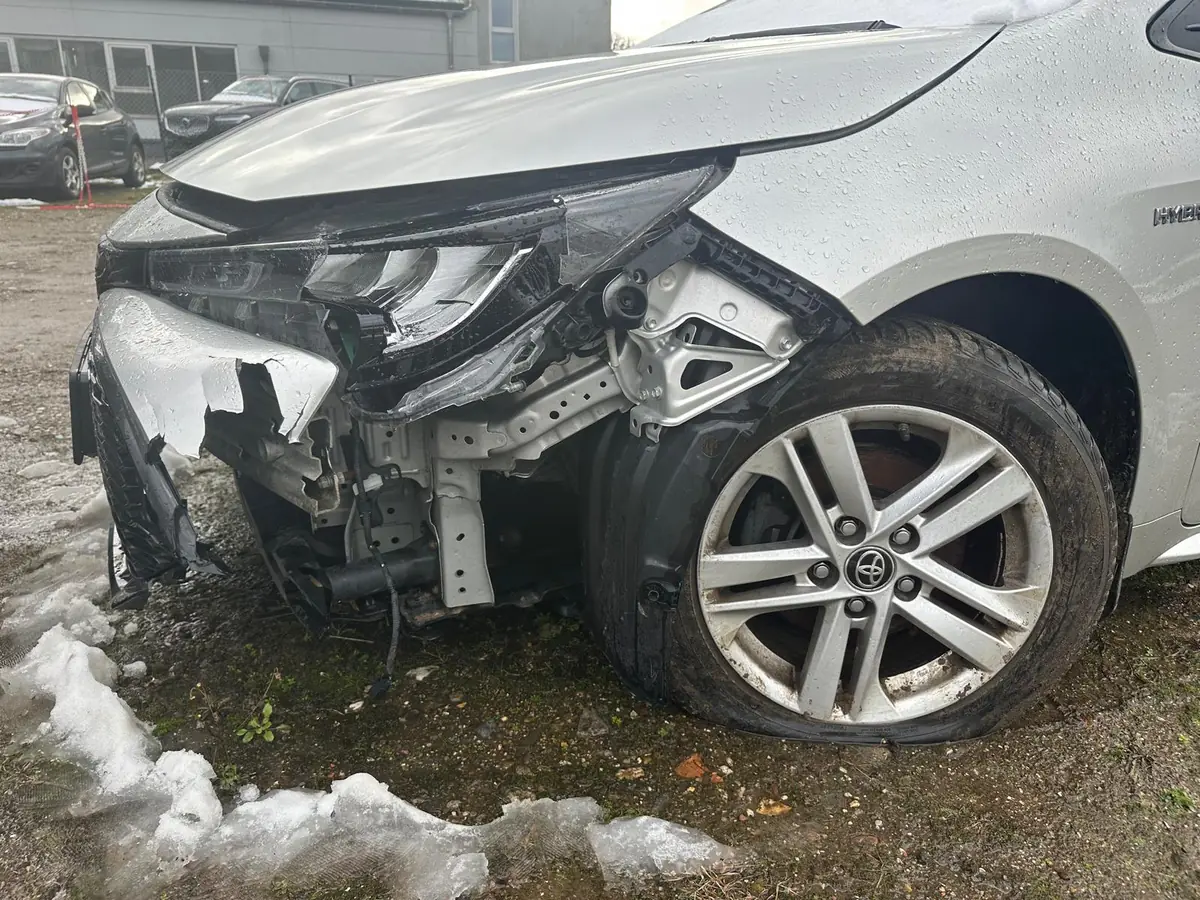 Silberner Toyota Corolla Hybrid mit schwerem Frontschaden an Stoßfänger, Scheinwerfer und Kotflügel