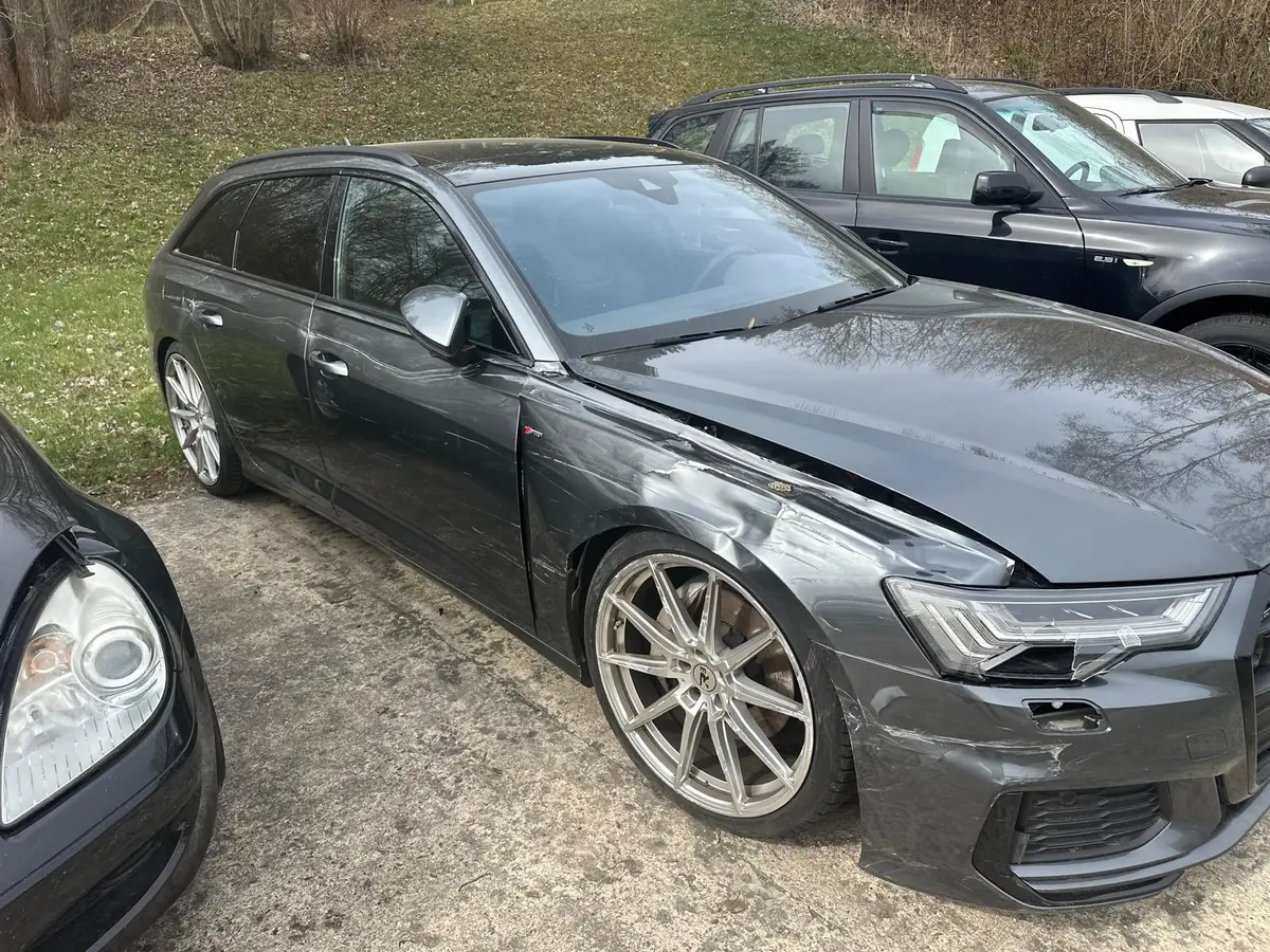 Grauer Audi A6 Avant mit Schäden an der Front und an der rechten Seite