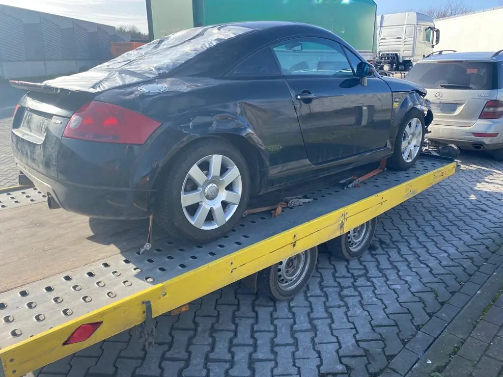 Unfallauto mit eingedrückter Seitenwand hinten, mit Gurten auf einem Autoanhänger gesichert