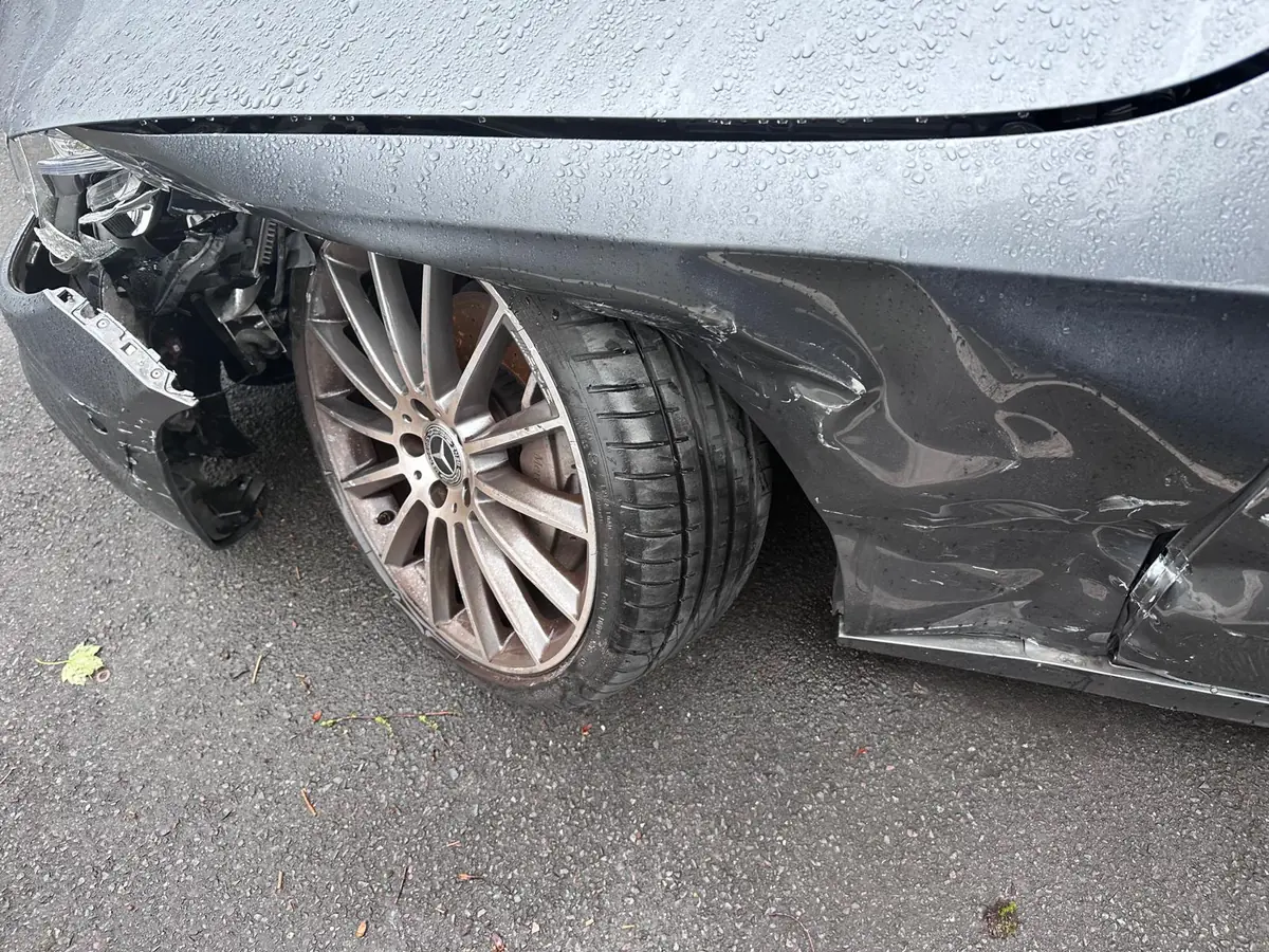 Grauer Mercedes mit schwerem Unfallschaden an Front und Seite: Stoßfänger abgerissen, Seitenwand eingedrückt