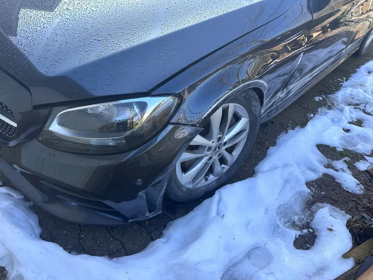 Dunkler Mercedes C-Klasse mit Schaden an Stoßfänger und Kotflügel vorne links